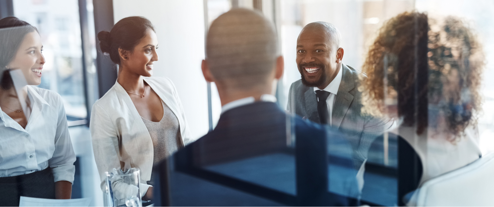 Executives discuss business growth strategies in a sunlit office, fostering alignment and leadership around the conference table.