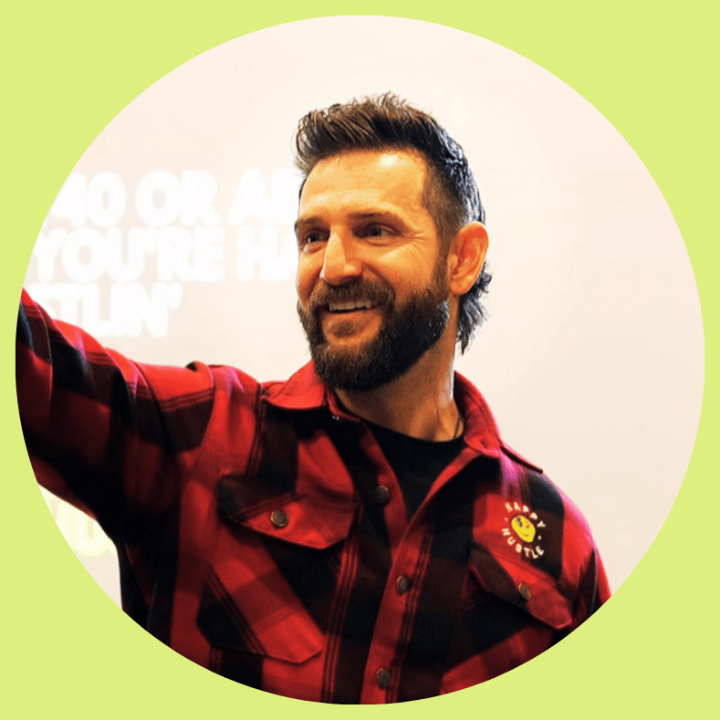 A smiling man in a red plaid shirt reaching out, representing approachable leadership and alignment with growth.