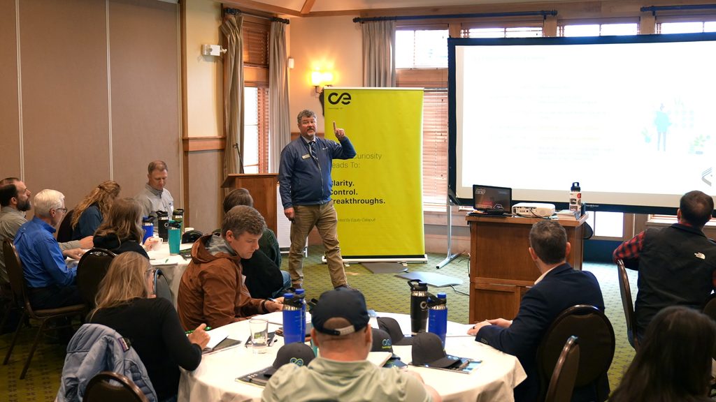A leader presents growth strategies to a team, emphasizing alignment and systems thinking in a conference setting.