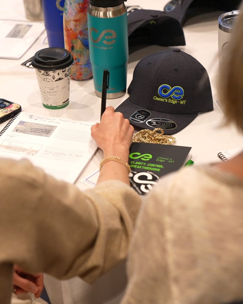 A leader planning sustainable growth in a notebook, surrounded by Owners Edge-MT branded materials and systems tools.