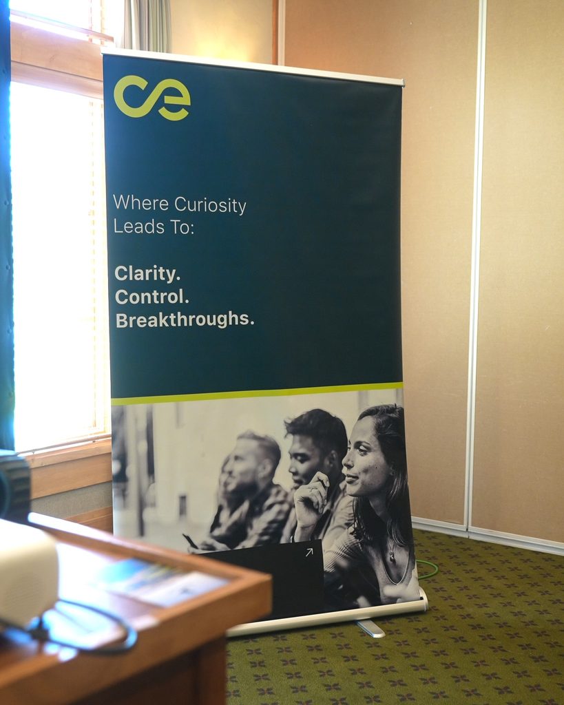 Vertical banner on clarity and growth above three professionals in a meeting focused on leadership and alignment.