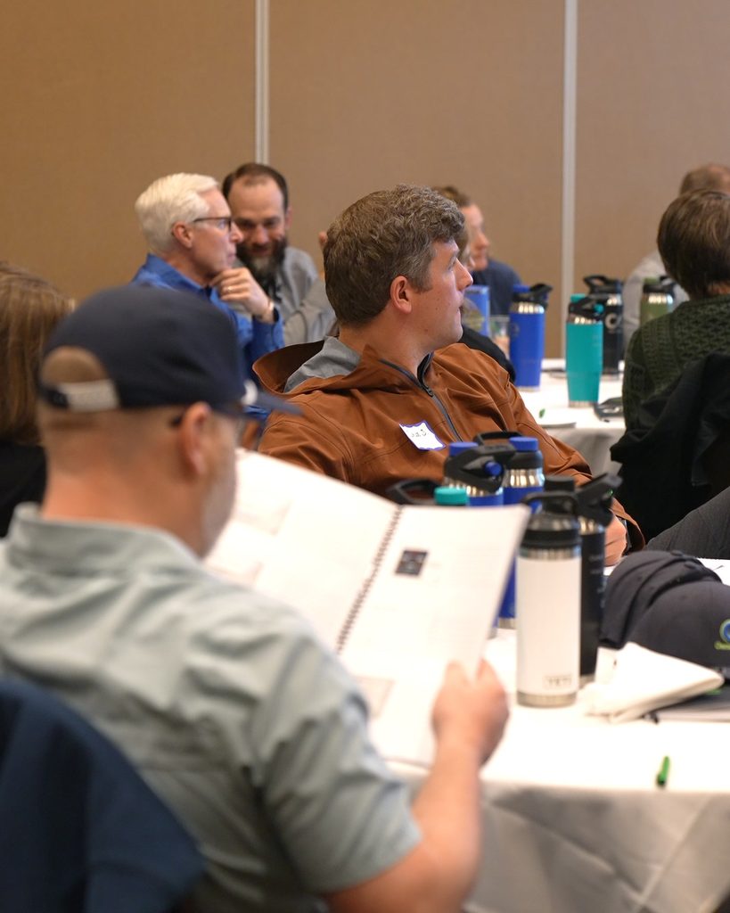 Professionals at a conference focused on leadership and alignment during a presentation on sustainable business growth.