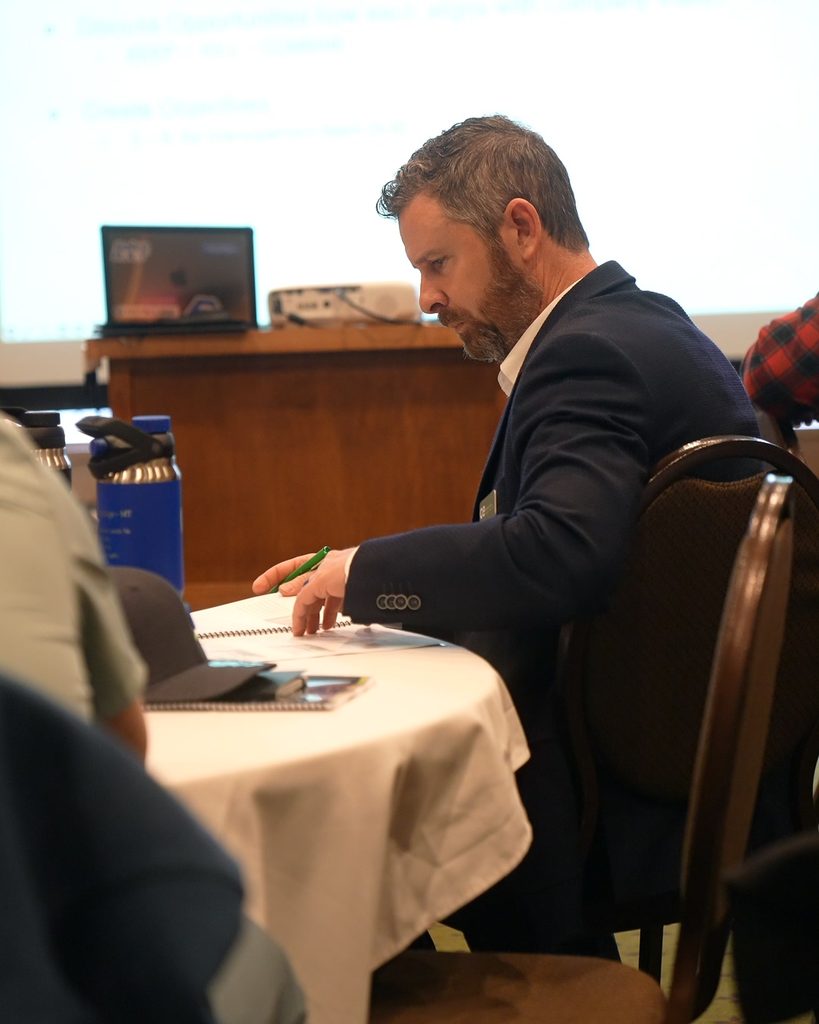 A professional in a blazer reviews meeting notes, focused on strategic alignment and sustainable growth.