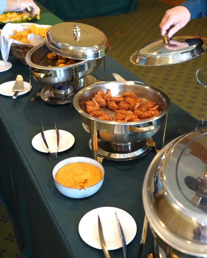 Professional catering service featuring stainless steel chafing dishes of breaded shrimp, reflecting operational scale.