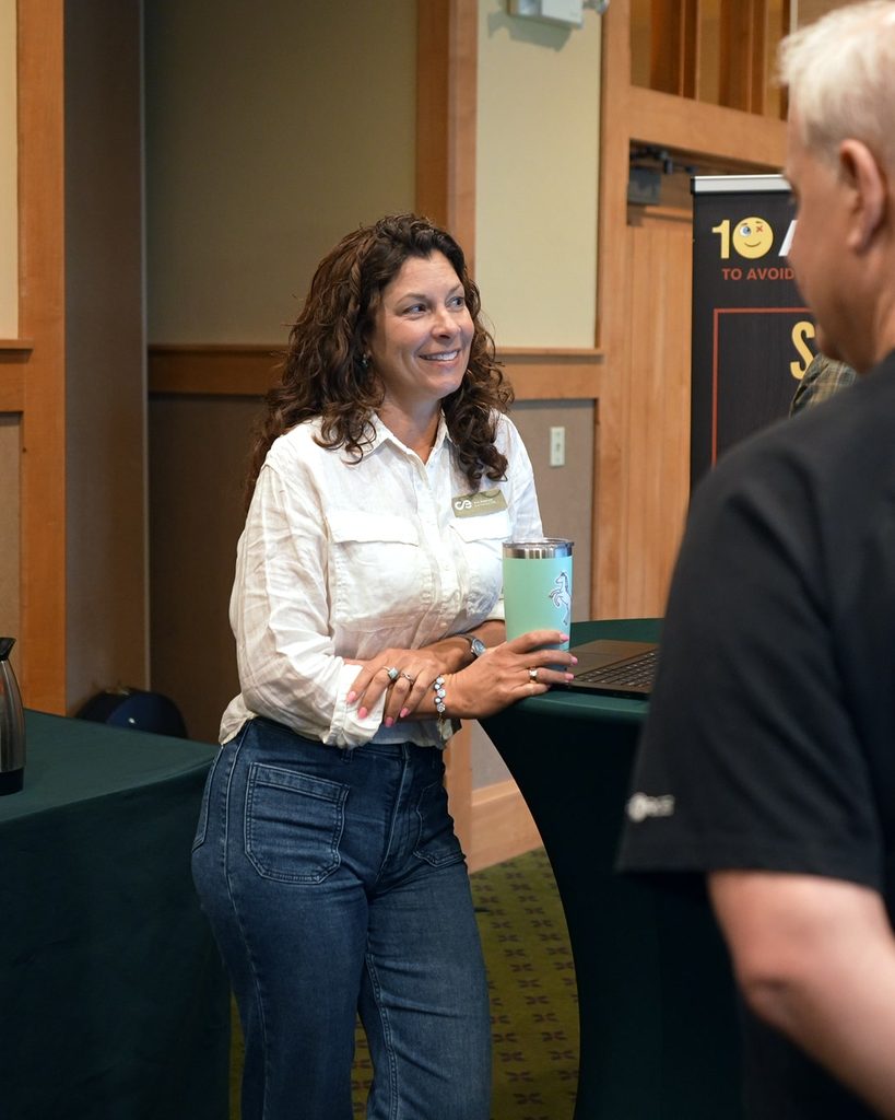 A professional woman in a white shirt smiles while holding a tumbler, embodying the alignment of intentional leadership.