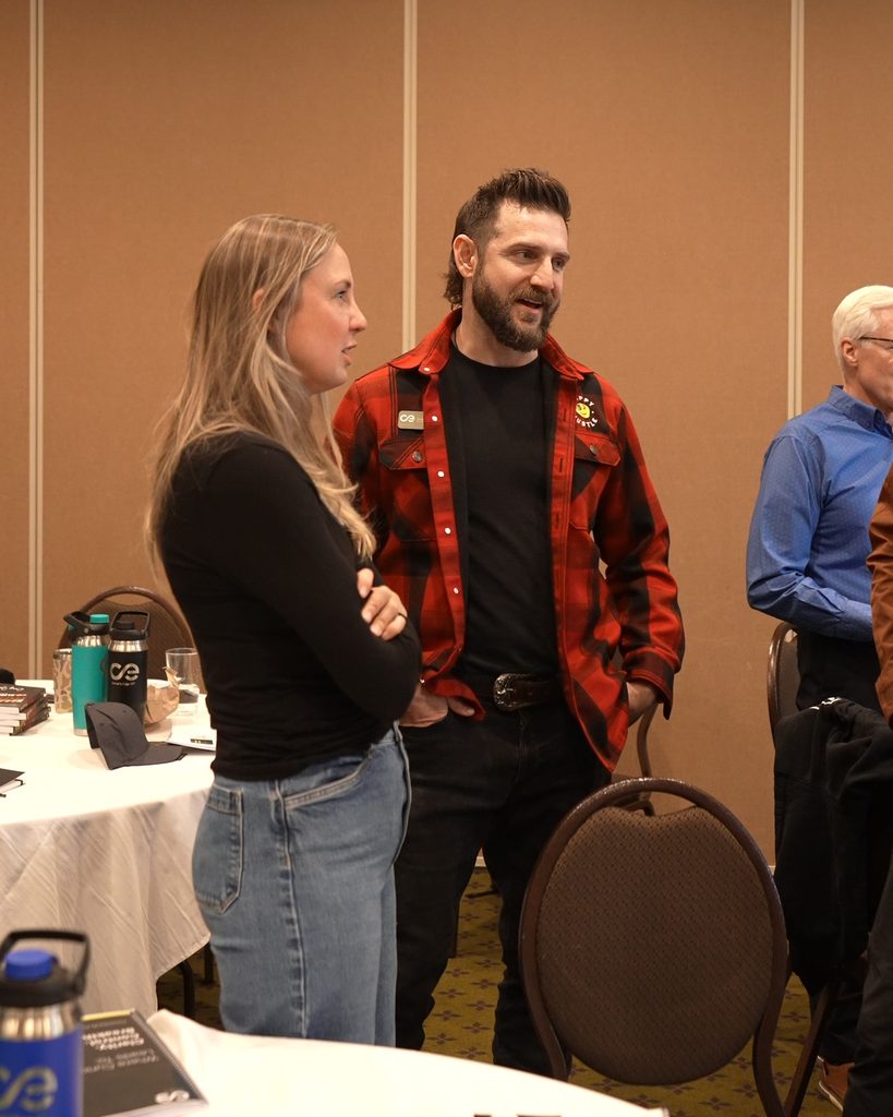 A woman and a man in a red plaid shirt discussing business alignment and scaling strategies.