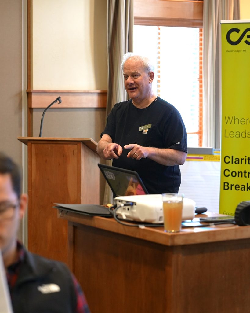 A leader presents a strategy for sustainable growth, gesturing in a meeting room near a branded corporate banner.
