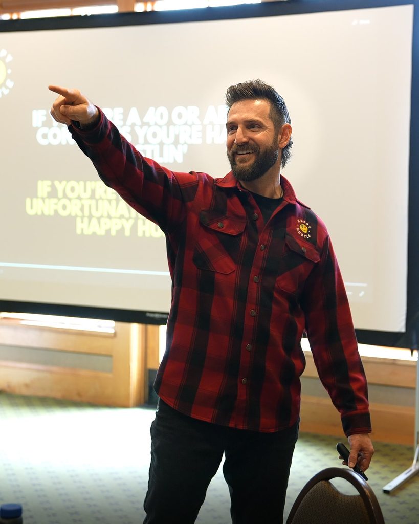 A workshop speaker leads a session on scaling and sustainable growth, gesturing toward a presentation screen.